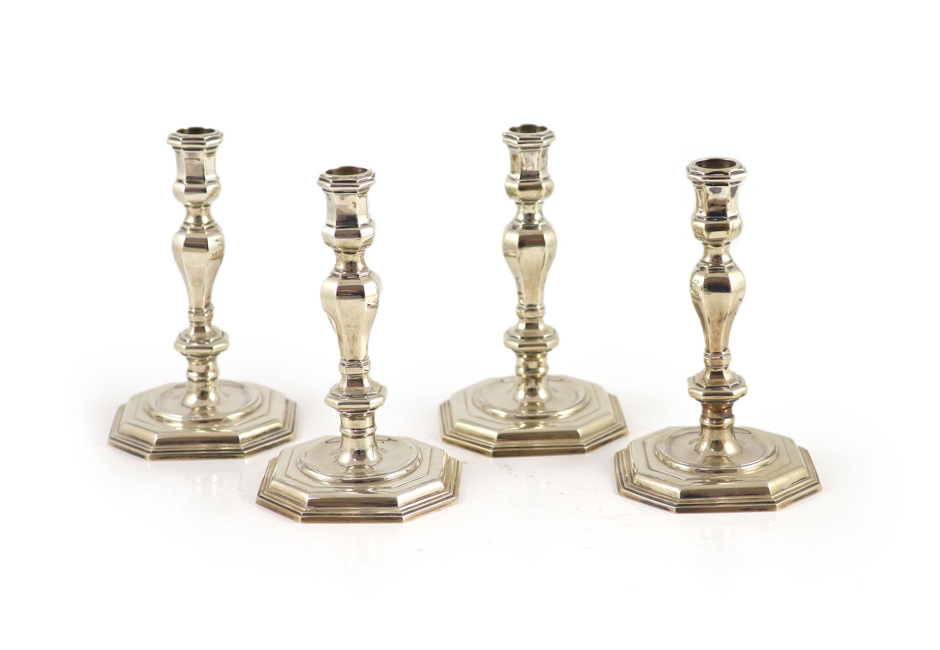 A set of four early 18th century design cast silver candlesticks